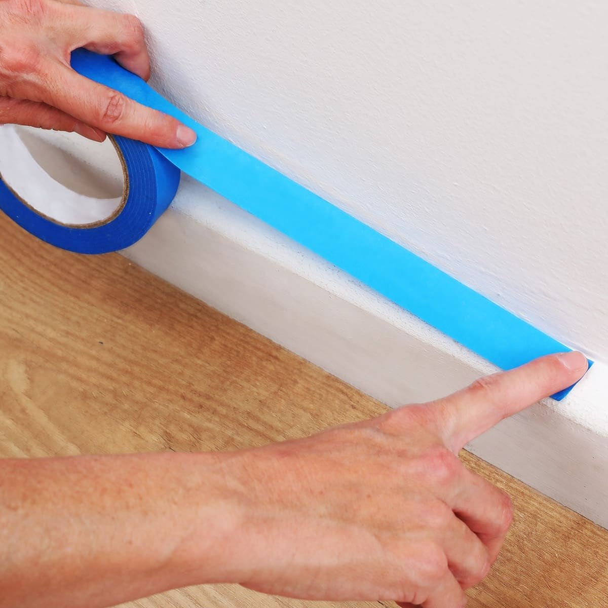 Applicazione del nastro per mascheratura blu su battiscopa per protezione durante la pittura