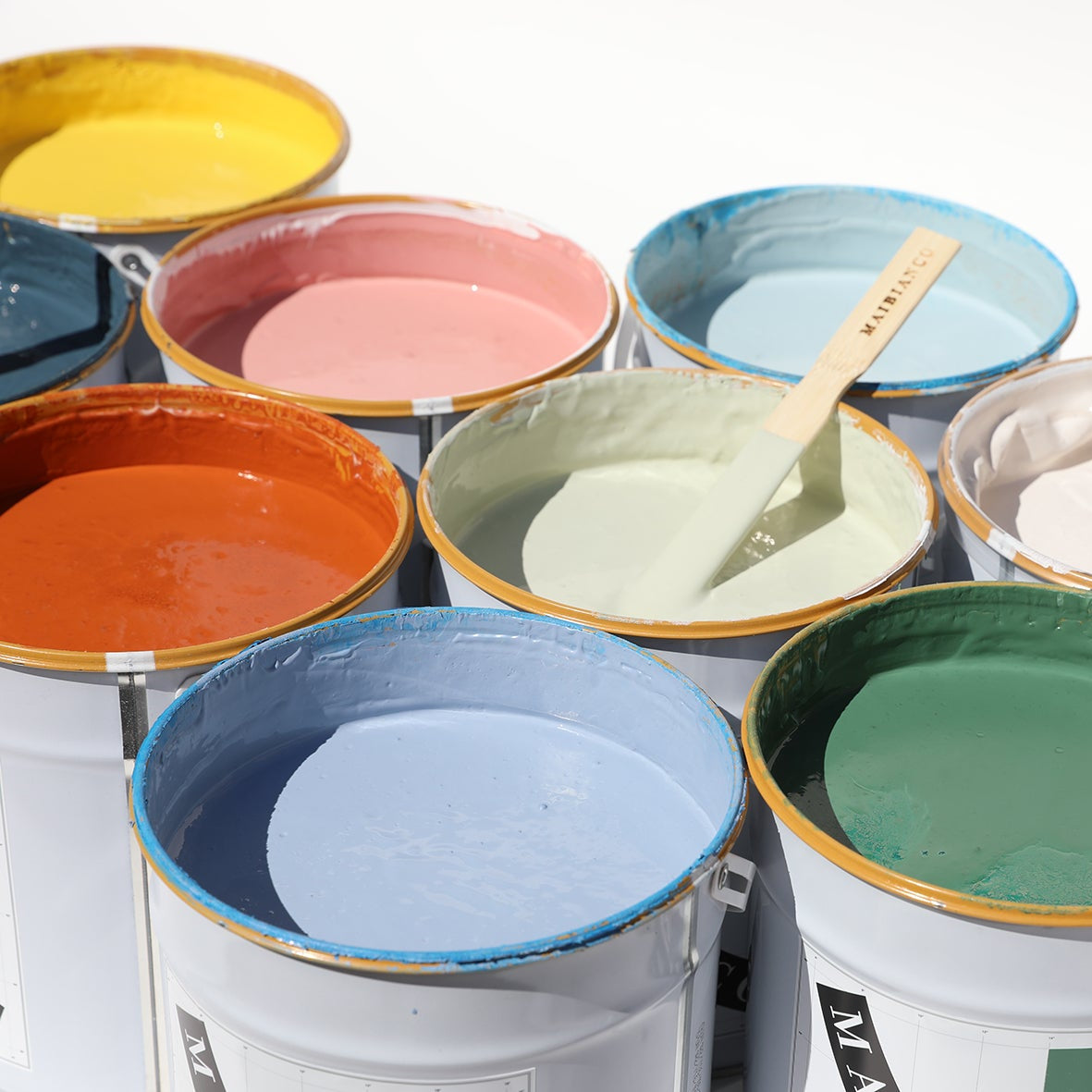 Barattoli di pittura Maibianco in vari colori opachi per interni, con stecche in legno per miscelazione